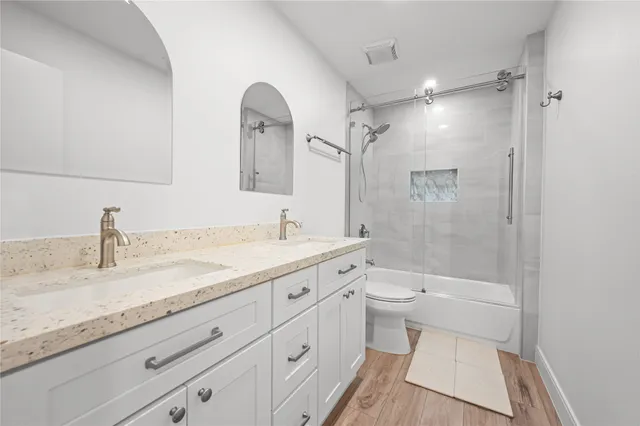 a bathroom with a granite countertop sink a toilet and shower