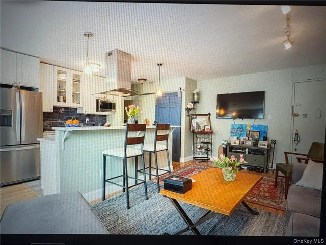 a living room with furniture a flat screen tv and a refrigerator