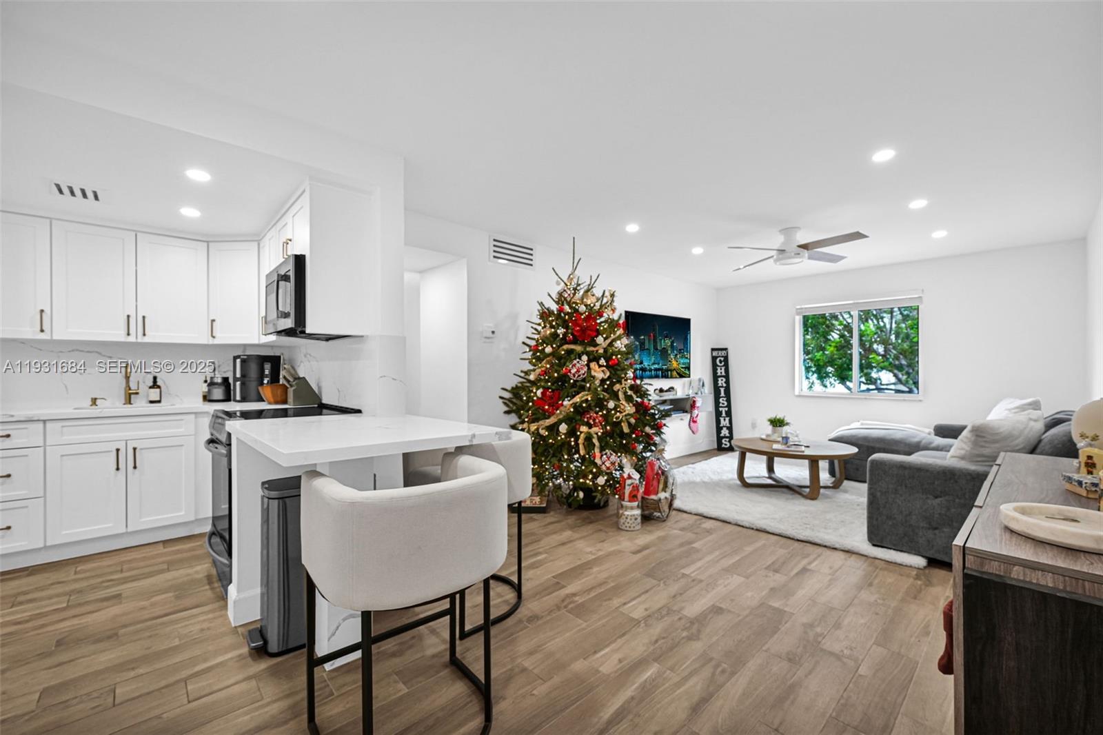 8609 Southwest 68th Court, Unit 24 Pinecrest, FL 33156 - Photo 11 of 40 a living room with furniture and a kitchen island with wooden floor