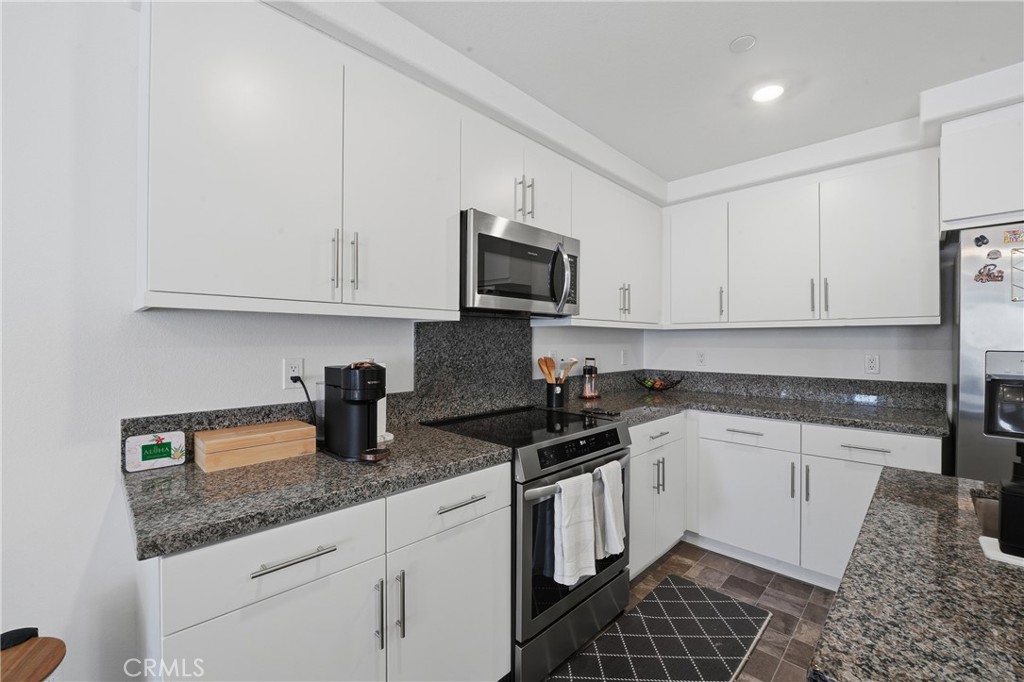 19210 Ash Grv Street Riverside, CA 92507 - Photo 16 of 38 a kitchen with granite countertop white cabinets and black appliances