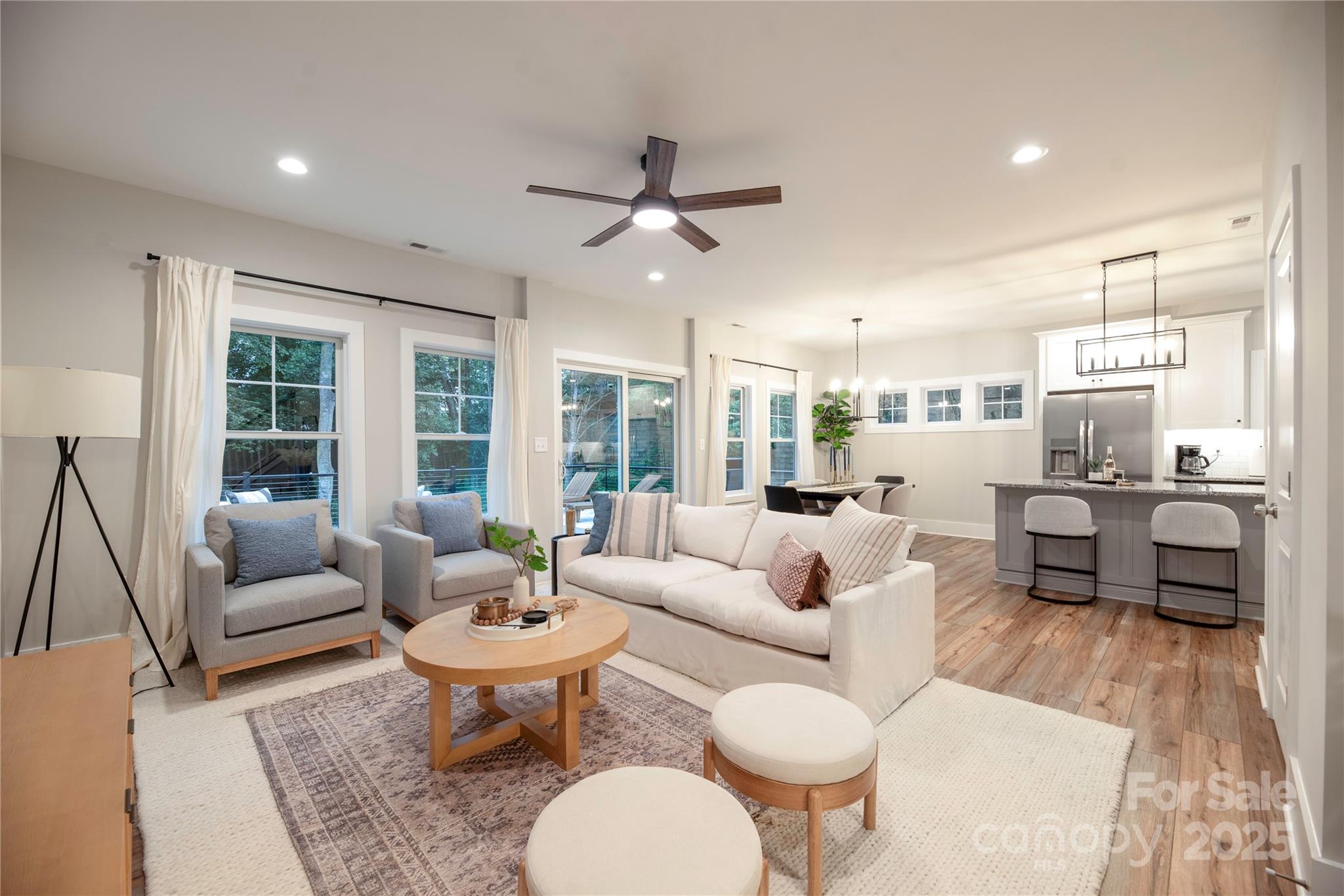 a living room with furniture kitchen view and a large window