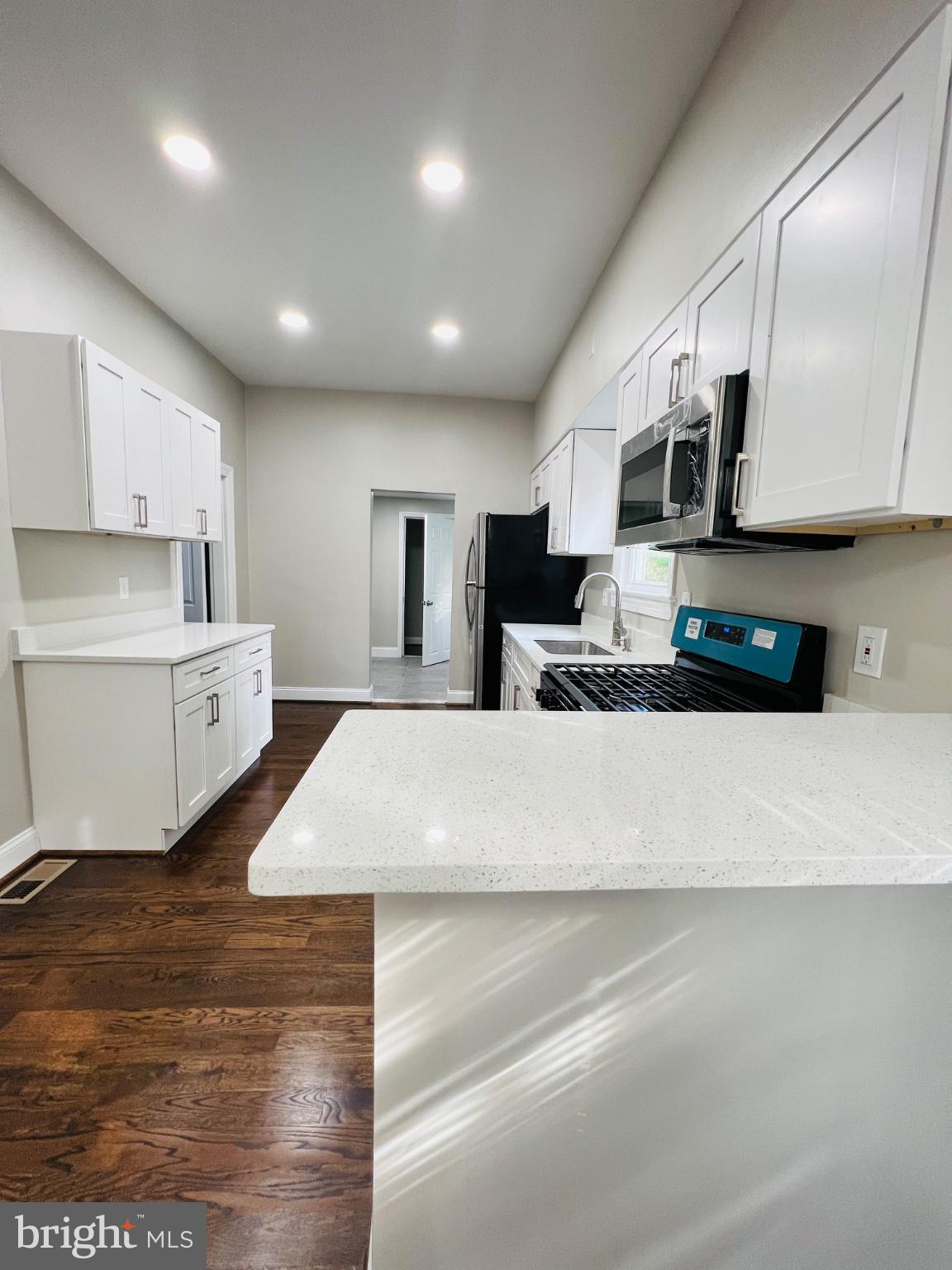 5709 Dade Street Capitol Heights, MD 20743 - Photo 8 of 30 a large white kitchen with kitchen island a sink stainless steel appliances and cabinets