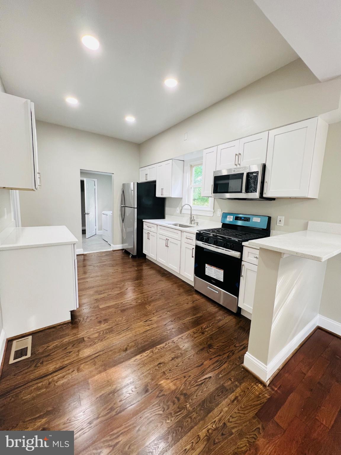 5709 Dade Street Capitol Heights, MD 20743 - Photo 9 of 30 a kitchen with stainless steel appliances granite countertop a stove top oven a sink dishwasher and a refrigerator with wooden floor
