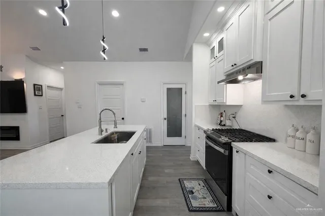 a kitchen that has a sink a stove and cabinets