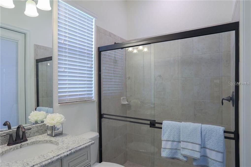 5528 Arnie Loop Lakewood Ranch, FL 34211 - Photo 30 of 59 a bathroom with a granite countertop sink a mirror and shower