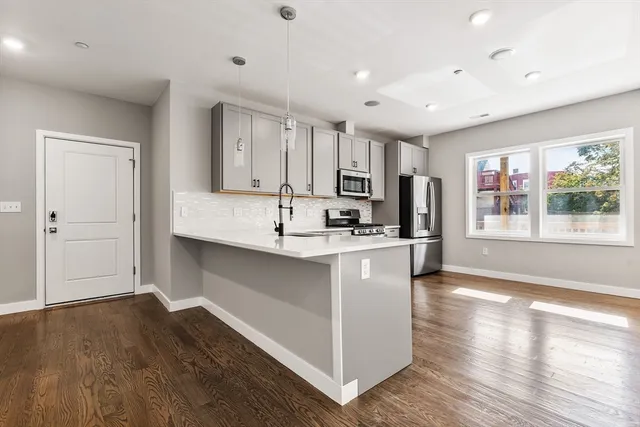 a kitchen with stainless steel appliances granite countertop a sink stove and wooden floor