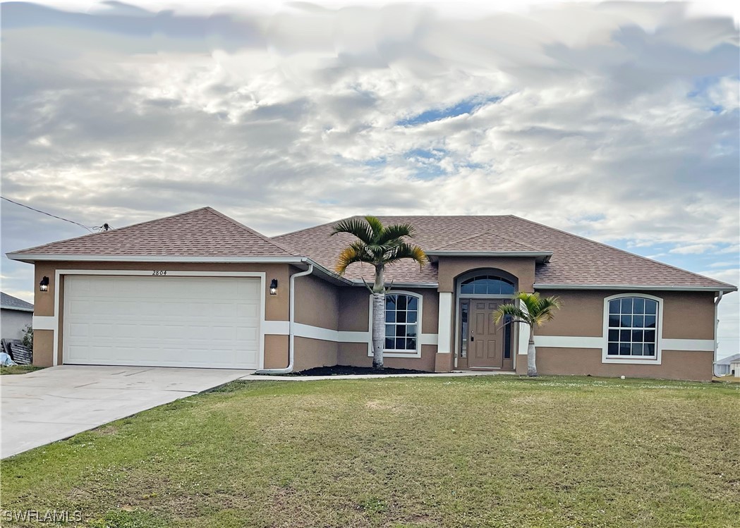 2804 Nelson Road North Cape Coral, FL 33993 - Photo 1 of 16 a front view of a house with a yard and garage