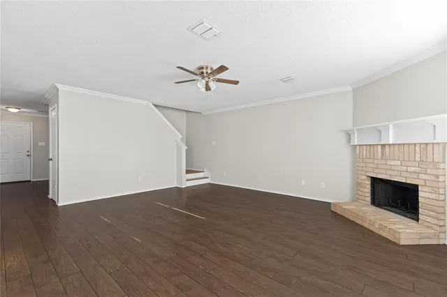 a view of an empty room with wooden floor and a fireplace