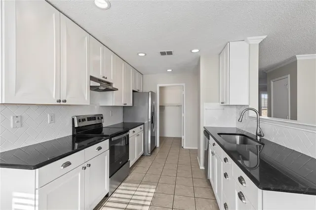 a kitchen with granite countertop white cabinets and stainless steel appliances