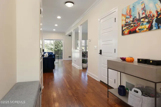 a hallway with a dining table chairs and couches with wooden floor