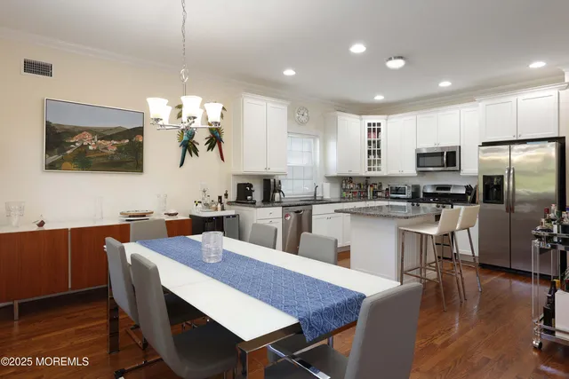 a kitchen with kitchen island a dining table chairs stainless steel appliances and cabinets