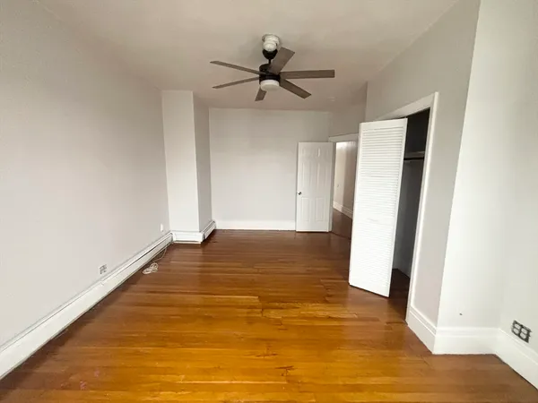 a view of empty room with wooden floor and fan