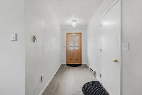 a view of a hallway with wooden floor and closet