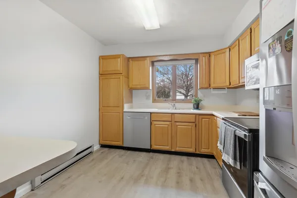 a kitchen with granite countertop white cabinets stainless steel appliances a sink and a window
