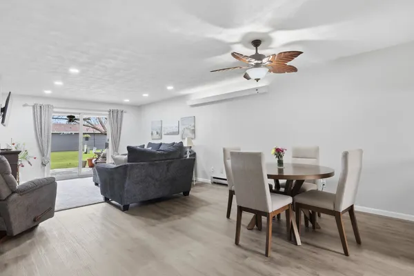 a living room with furniture and a dining table with wooden floor