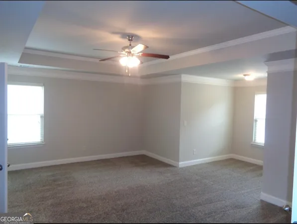 en empty room with windows and chandelier fan