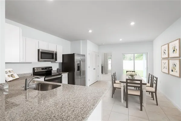 a kitchen with stainless steel appliances granite countertop a stove top oven a sink a dining table and chairs