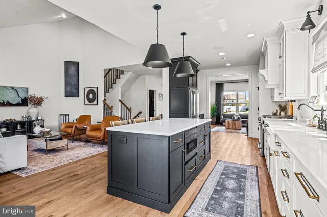 a large kitchen with kitchen island a large counter top space a sink a stove and wooden floor