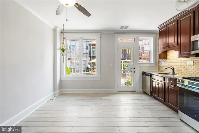 a view of kitchen with stainless steel appliances granite countertop a stove top oven a sink dishwasher a dining table and chairs with wooden floor