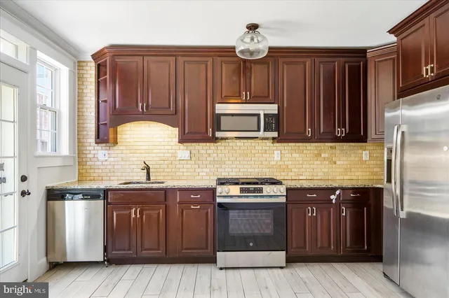a kitchen with stainless steel appliances granite countertop wooden cabinets a stove a sink and dishwasher