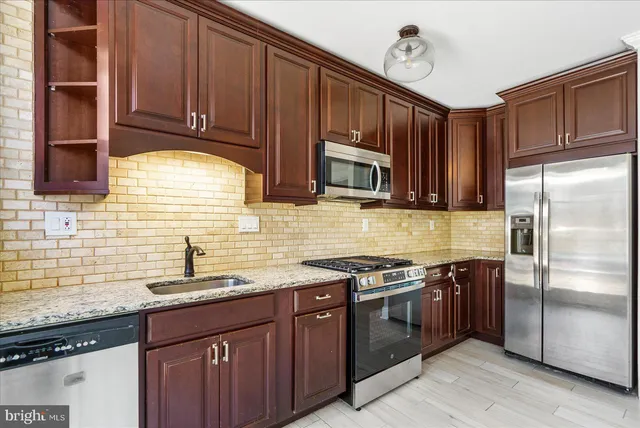a kitchen with stainless steel appliances granite countertop a stove a sink dishwasher and a refrigerator