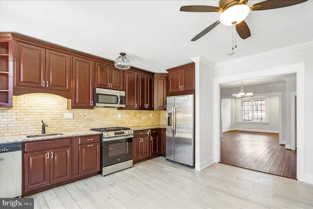 a kitchen with stainless steel appliances granite countertop a refrigerator a sink dishwasher a stove with wooden cabinets and floor