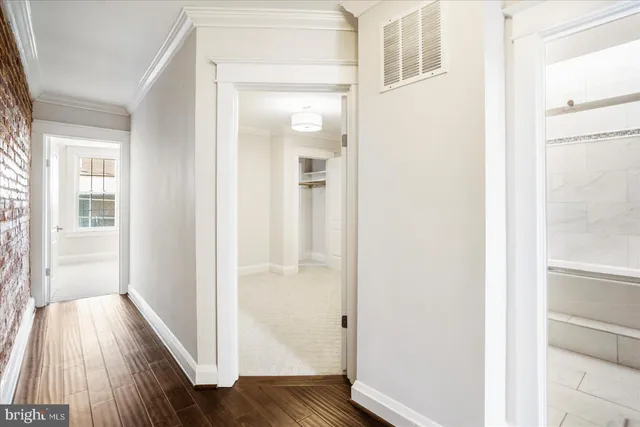 a view of a hallway with wooden floor and a bathroom