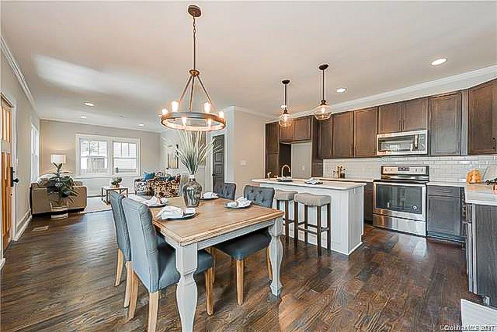 2116 Rozzelles Ferry Road Charlotte, NC 28208 - Photo 9 of 24 a open kitchen with stainless steel appliances granite countertop a stove a refrigerator a kitchen island a dining table and chairs with wooden floor