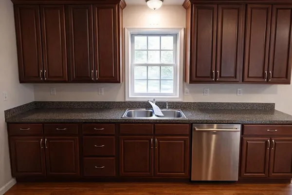 a kitchen with granite countertop wooden cabinets and a sink
