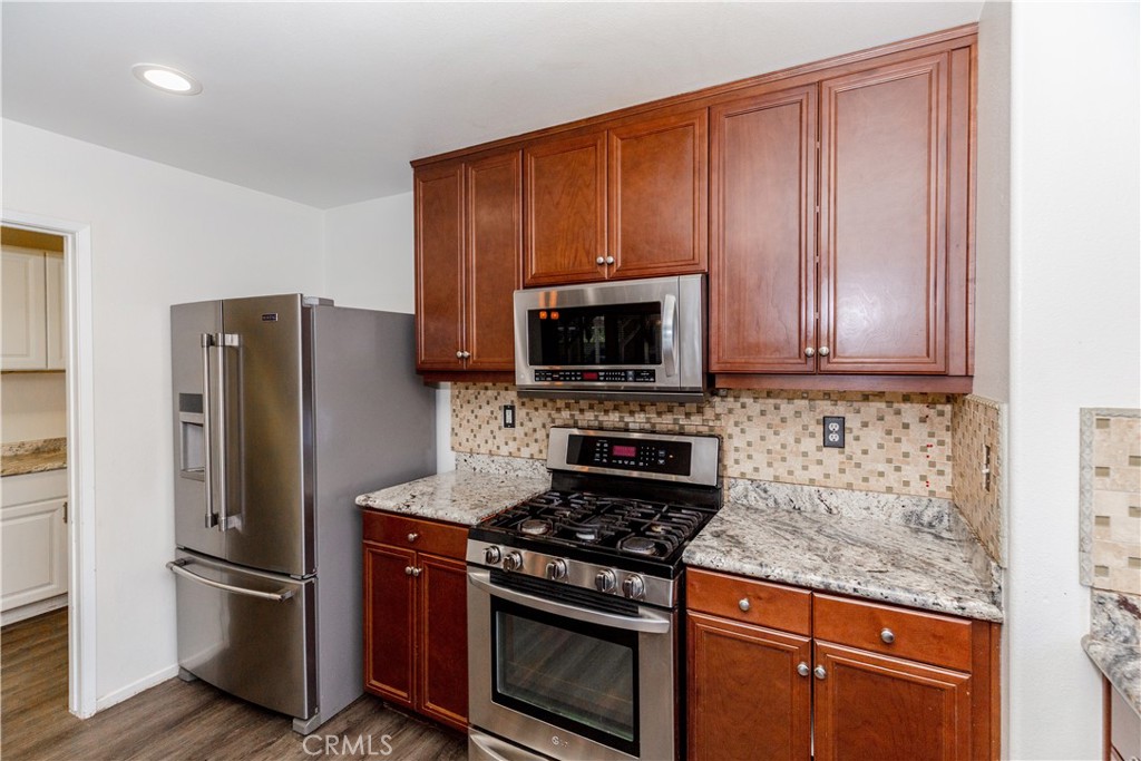 1457 Faircliff Street Beaumont, CA 92223 - Photo 9 of 37 a kitchen with stainless steel appliances granite countertop a stove a refrigerator and a microwave