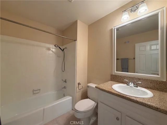 a bathroom with a granite countertop sink a toilet a mirror and shower