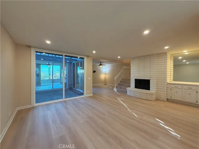 a view of an empty room with wooden floor and windows