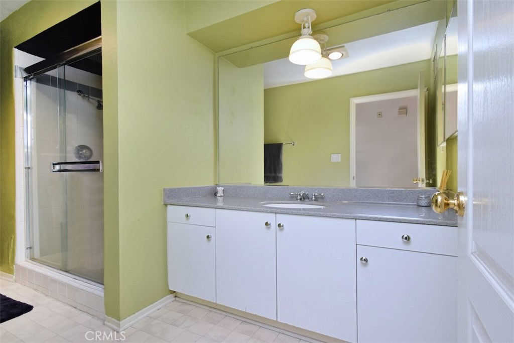 5050 Coldwater Canyon Avenue, Unit 306 Sherman Oaks, CA 91423 - Photo 19 of 24 a bathroom with a granite countertop sink a mirror and a shower