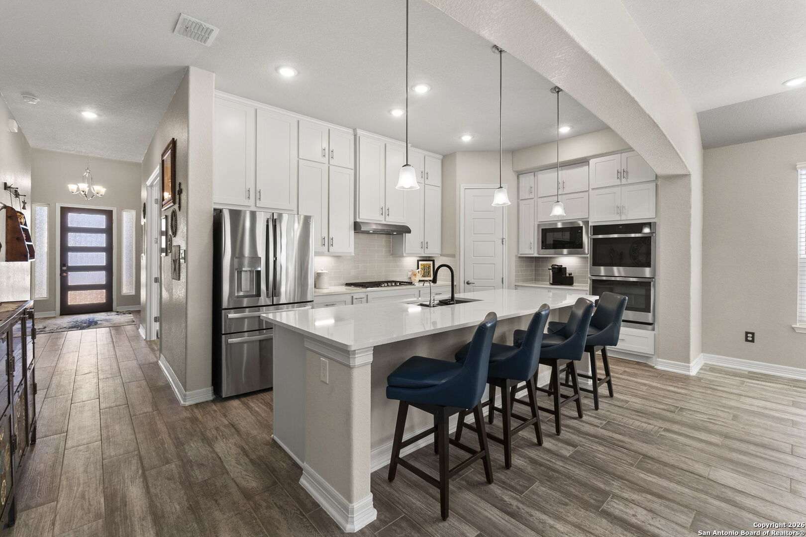 705 Tree Top Pass New Braunfels, TX 78130 - Photo 5 of 49 a kitchen with stainless steel appliances kitchen island granite countertop a refrigerator a stove a sink a dining table and chairs with wooden floor
