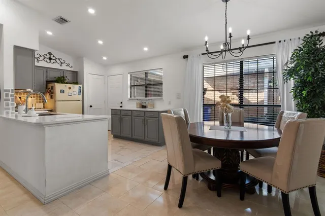 a kitchen with kitchen island a dining table chairs and white cabinets