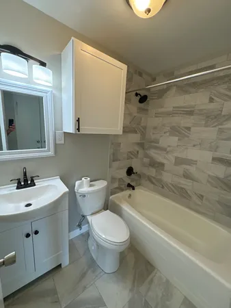 a bathroom with a toilet a sink a mirror and bathtub