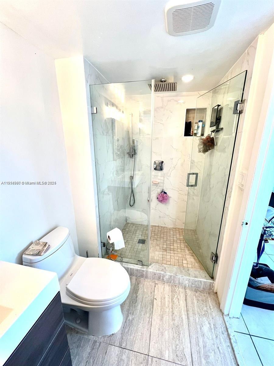 8001 Crespi Boulevard, Unit 6D Miami Beach, FL 33141 - Photo 18 of 29 a white toilet sitting next to a bathroom sink and tub