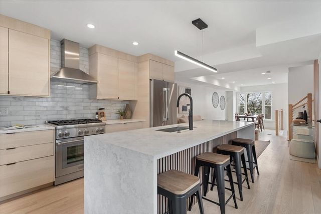 a kitchen with stainless steel appliances granite countertop a stove a sink a kitchen island with chairs and wooden floor