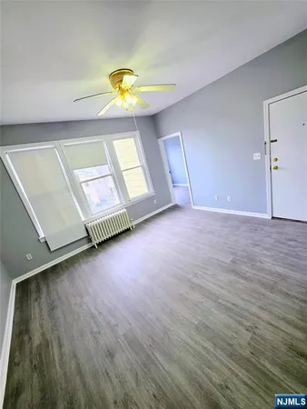 a view of an empty room with window and wooden floor