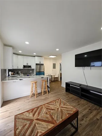 a living room with stainless steel appliances furniture and a kitchen view
