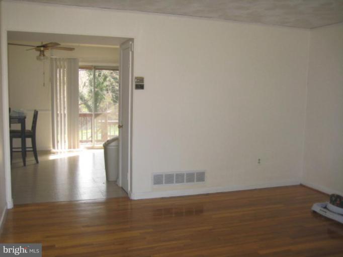 4835 Melbourne Road Baltimore, MD 21229 - Photo 2 of 7 a view of an empty room with wooden floor and a window