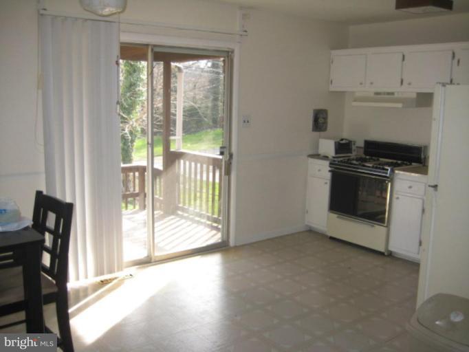 4835 Melbourne Road Baltimore, MD 21229 - Photo 3 of 7 a view of a kitchen with a stove wooden table and chairs