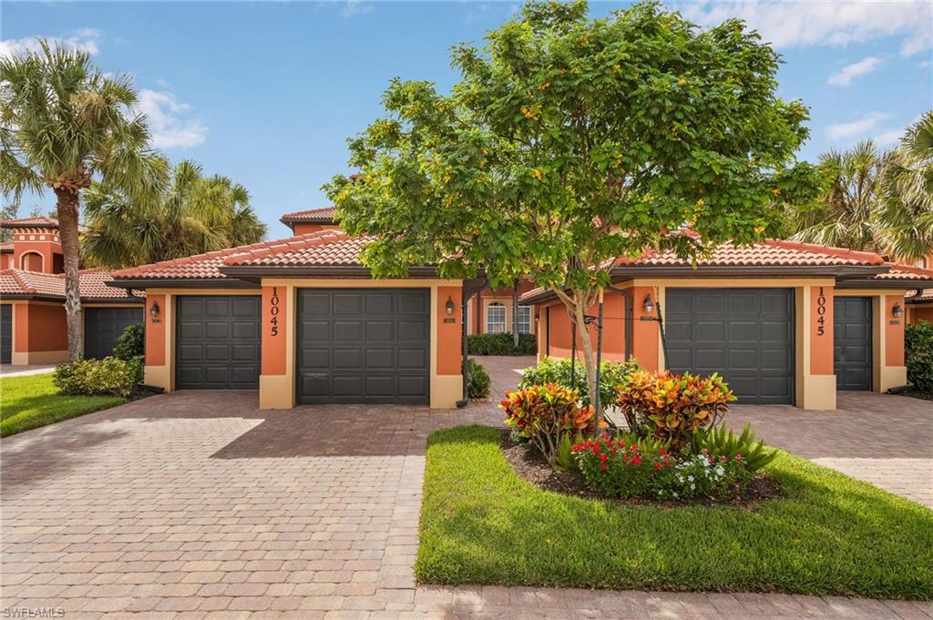 a front view of a house with a garden and a tree