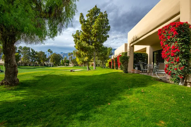 a view of a house with a big yard and palm trees