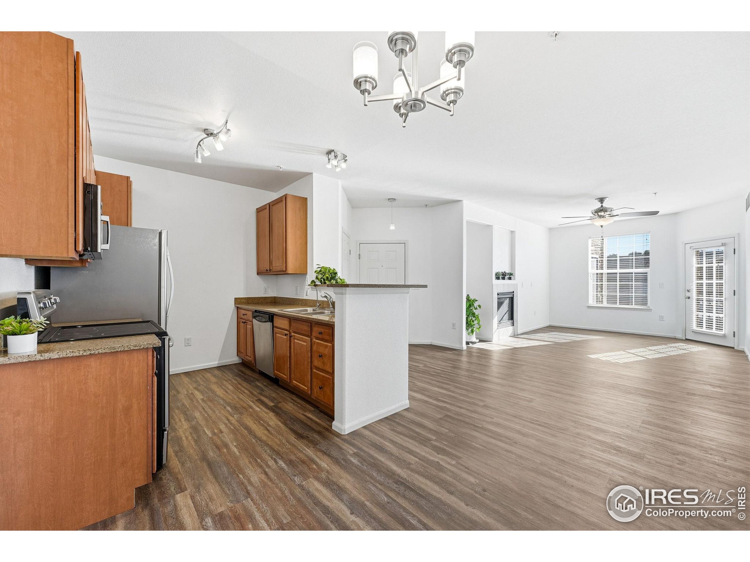 1425 Blue Sky Circle, Unit 15105 Erie, CO 80516 - Photo 11 of 45 a kitchen with stainless steel appliances granite countertop a stove top oven a sink dishwasher and a refrigerator with wooden floor