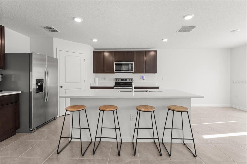 13691 Southwest 69th Terrace Ocala, FL 34473 - Photo 11 of 44 a kitchen with stainless steel appliances kitchen island granite countertop a refrigerator and a stove top oven