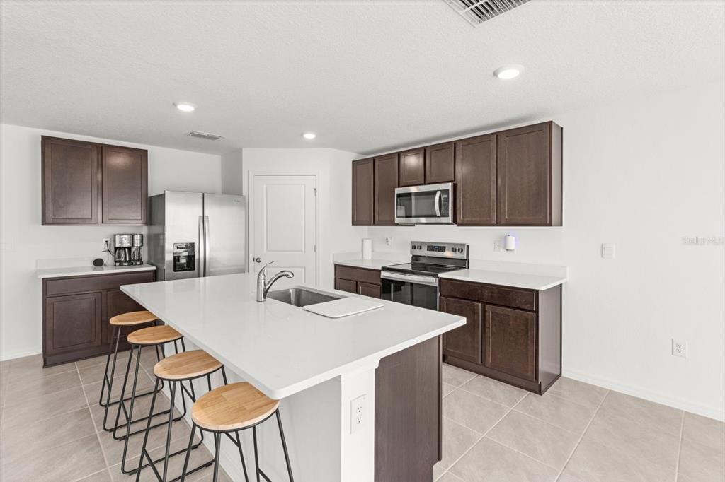 13691 Southwest 69th Terrace Ocala, FL 34473 - Photo 12 of 44 a kitchen with stainless steel appliances a stove top oven a refrigerator a sink and a refrigerator with wooden floor