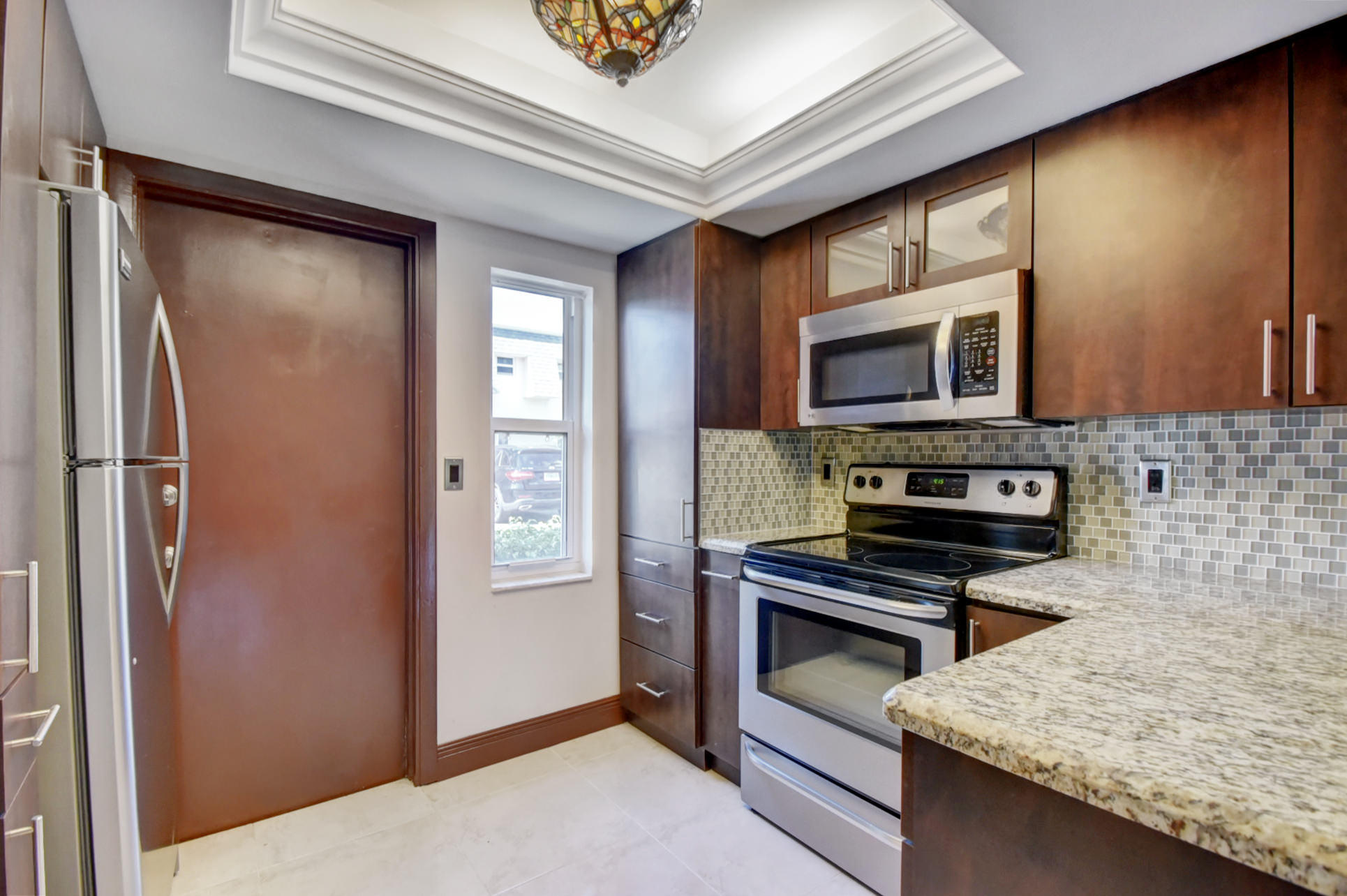 1845 Northwest 4th Avenue, Unit 16 Boca Raton, FL 33432 - Photo 12 of 37 a kitchen with stainless steel appliances granite countertop a refrigerator a stove and a sink