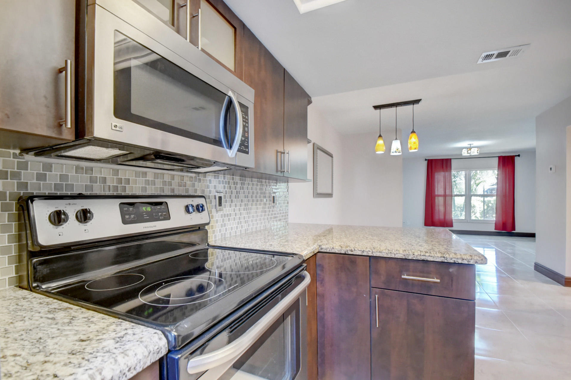1845 Northwest 4th Avenue, Unit 16 Boca Raton, FL 33432 - Photo 14 of 37 a kitchen with granite countertop a stove microwave and sink
