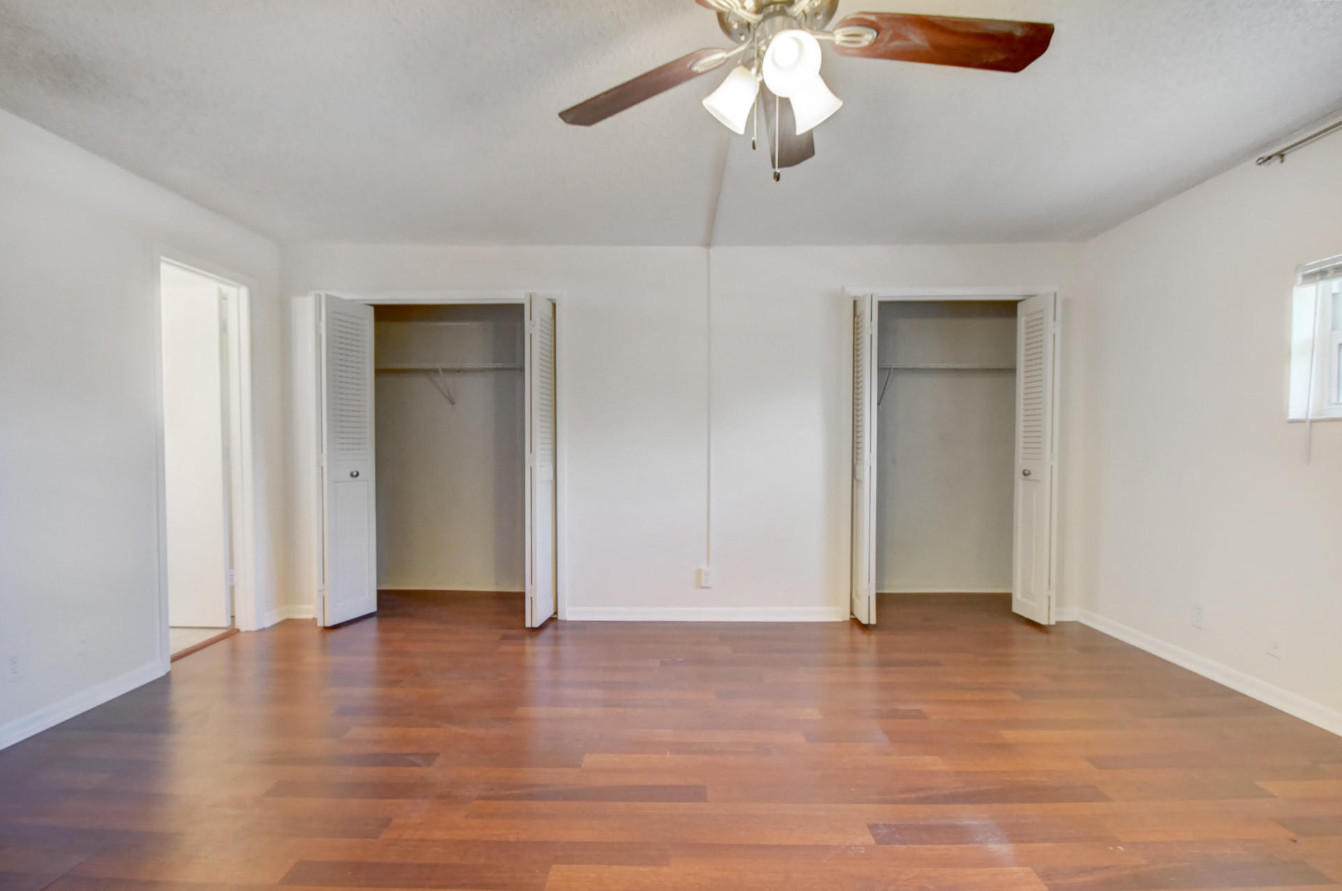 1845 Northwest 4th Avenue, Unit 16 Boca Raton, FL 33432 - Photo 28 of 37 an empty room with wooden floor chandelier fan and closet area